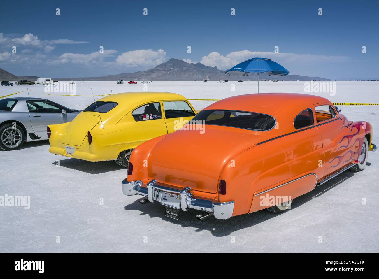 Maßgeschneiderte Zuschauerautos bei der Bonneville Speed Week auf Bonneville Salt Flats. Gelbes Henry J und Mercury Coupe mit Flammen, beide aus den frühen 1950er Jahren Stockfoto