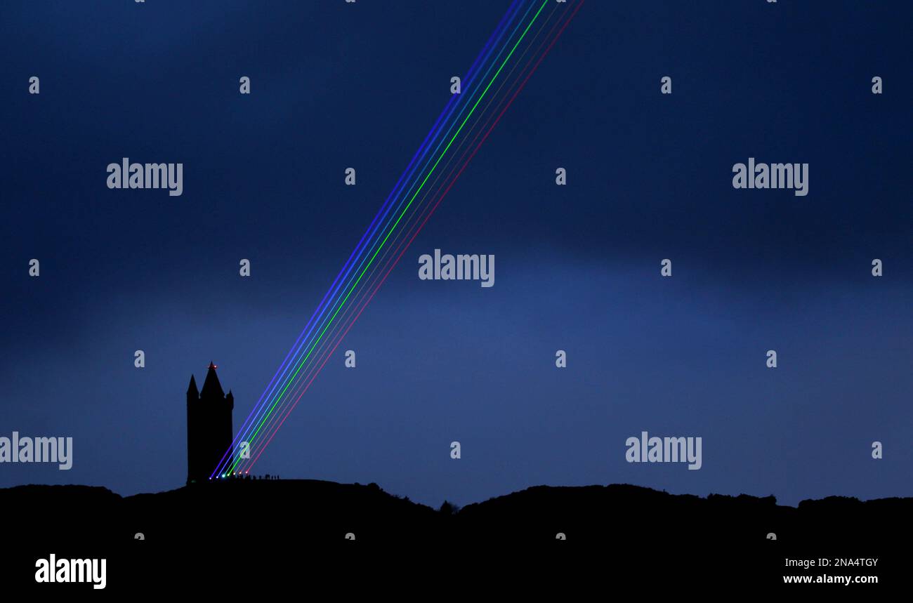 The Global Rainbow is projected into the night sky from Scrabo Tower, Newtownards, Northern Ireland, Friday, March 16, 2012. The large scale outdoor laser projection created by New York artist Yvette Mattern is visible across the night sky, the event signals 100 days to go until the opening of the London 2012 Festival which is a tweleve-week festival of arts running parallel to the Olympic Games taking place in London. (AP Photo/Peter Morrison) Stockfoto