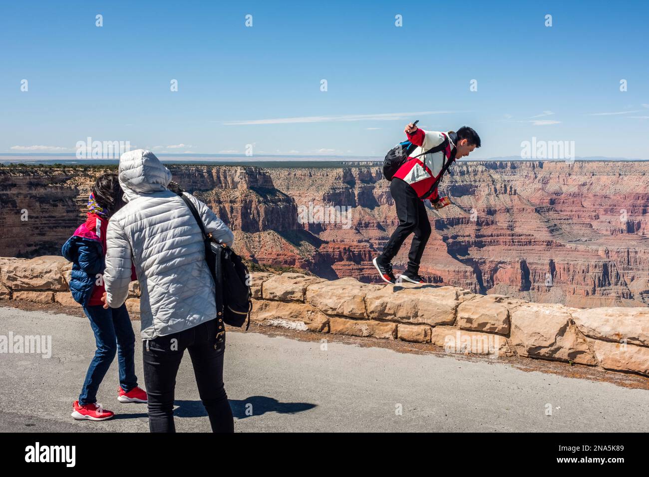 Touristen, die so tun, als würden sie vom Mohave Point, South Rim, Arizona, USA, in den Grand Canyon fallen Stockfoto