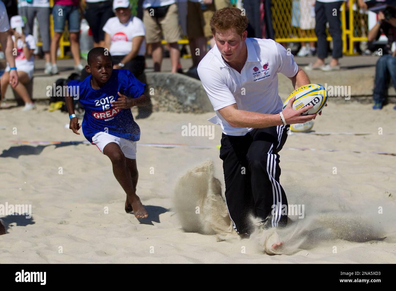 Britain's Prince Harry, plays rugby with kids at Flamengo's beach in Rio de Janeiro, Brazil, Saturday March 10, 2012. Harry is in Brazil at the request of the British government on a trip to promote ties and emphasize the transition from the upcoming 2012 London Games to the 2016 Olympics in Rio de Janeiro. (AP Photo/Felipe Dana) Stockfoto