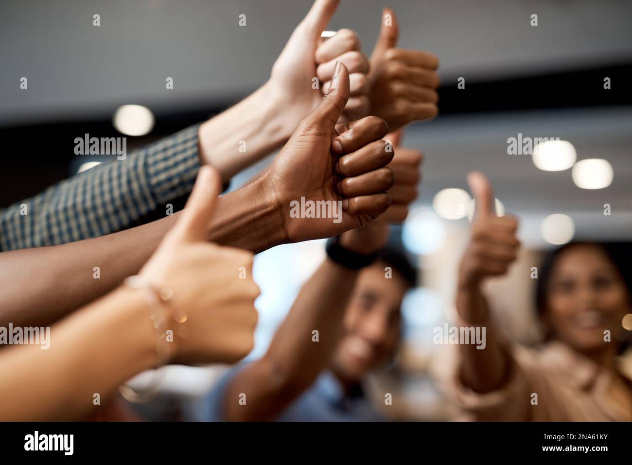 Die Wertschätzung der Mitarbeiter zahlt sich aus. Eine Gruppe von unbekannten Geschäftsleuten, die in einem modernen Büro Daumen nach oben zeigen. Stockfoto