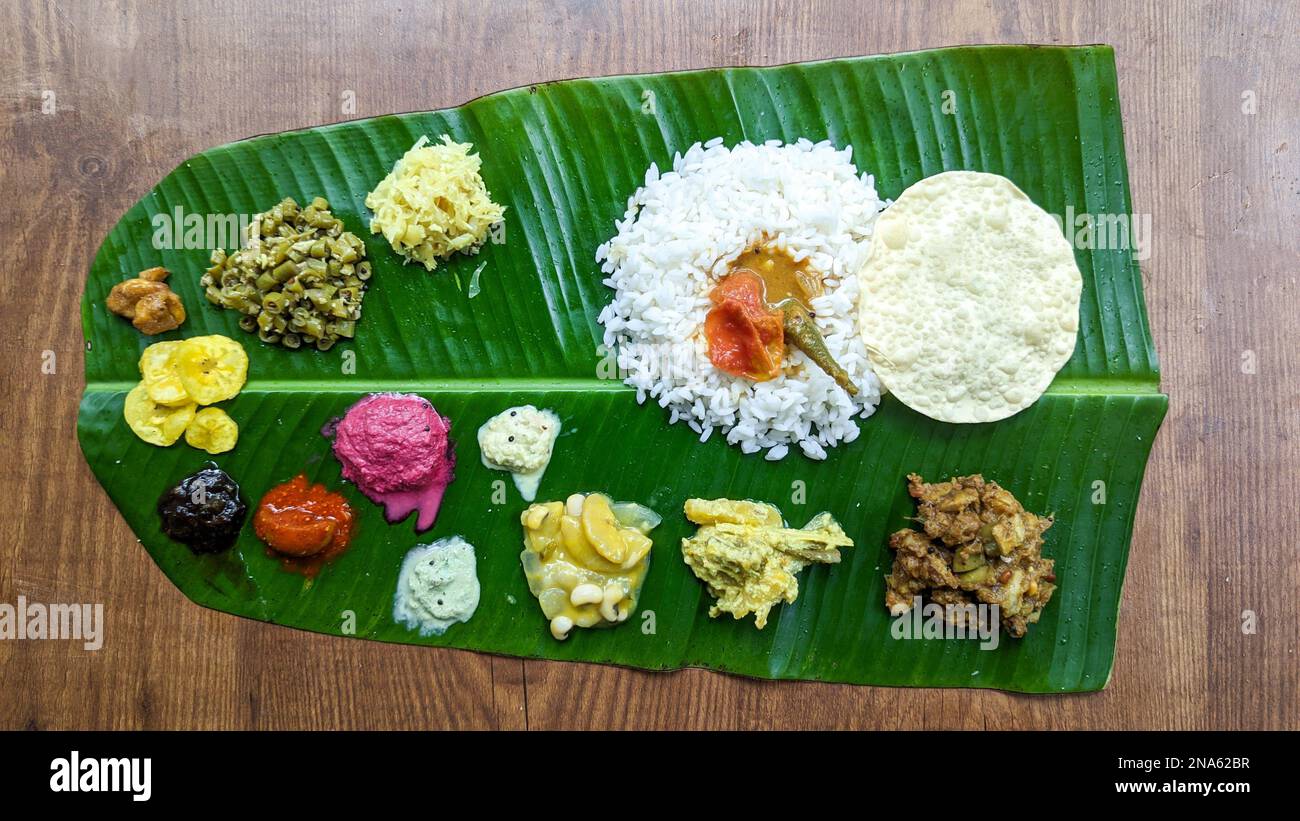 Traditionelle südindische Speiseplatte mit Reis und anderen abwechslungsreichen Speisen, serviert auf einem Bananenblatt für ein Festival oder einen Anlass Stockfoto