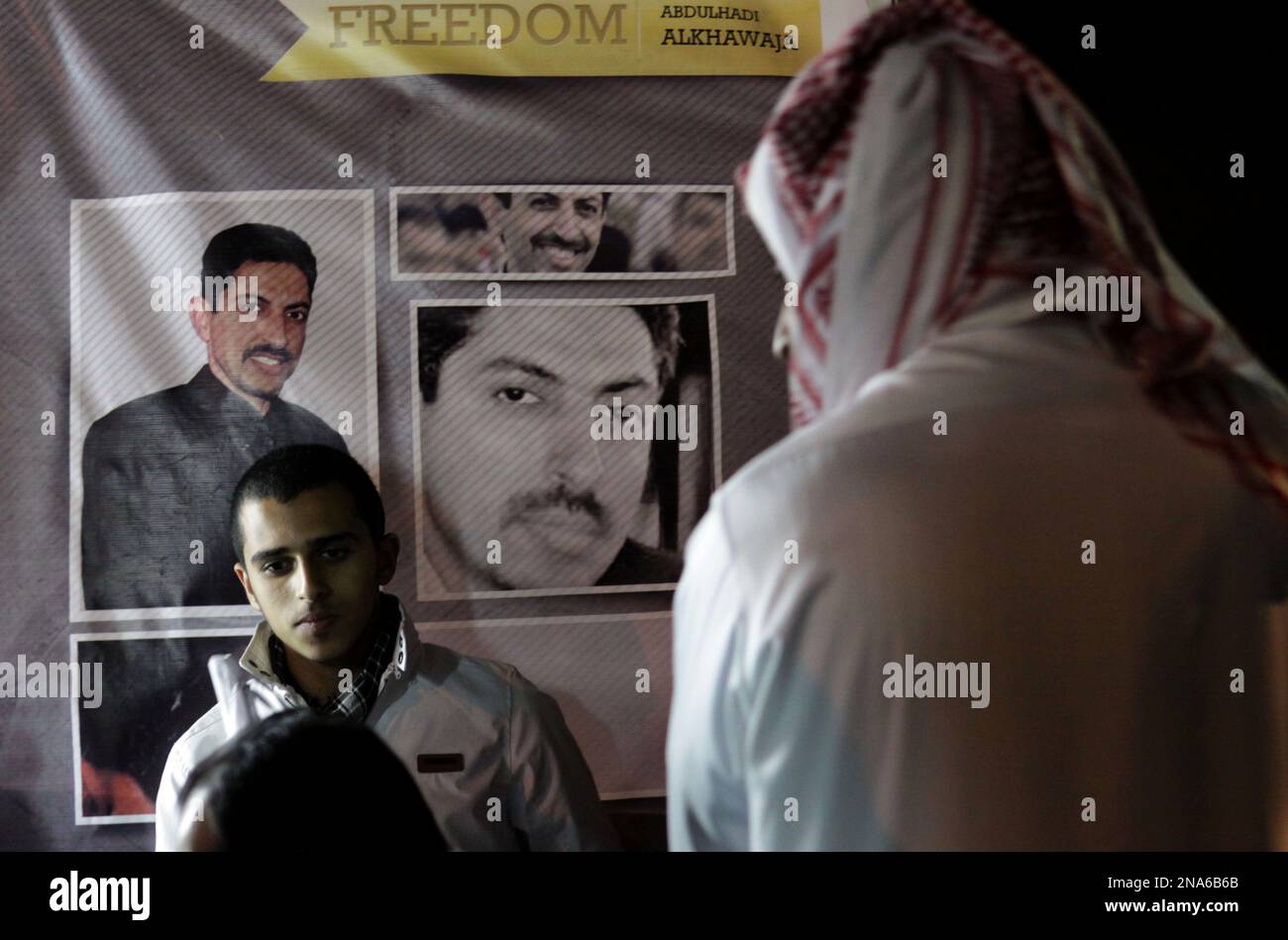 Bahraini anti-government protesters gathered in front of pictures of jailed Bahraini opposition human rights activist Abdulhadi al-Khawaja on the 27th day of his prison hunger strike, Wednesday, March 7, 2012, in Muqsha, Bahrain, outside the capital of Manama, during a rally demanding an elected government in the Gulf island kingdom. (AP Photo/Hasan Jamali) Stockfoto