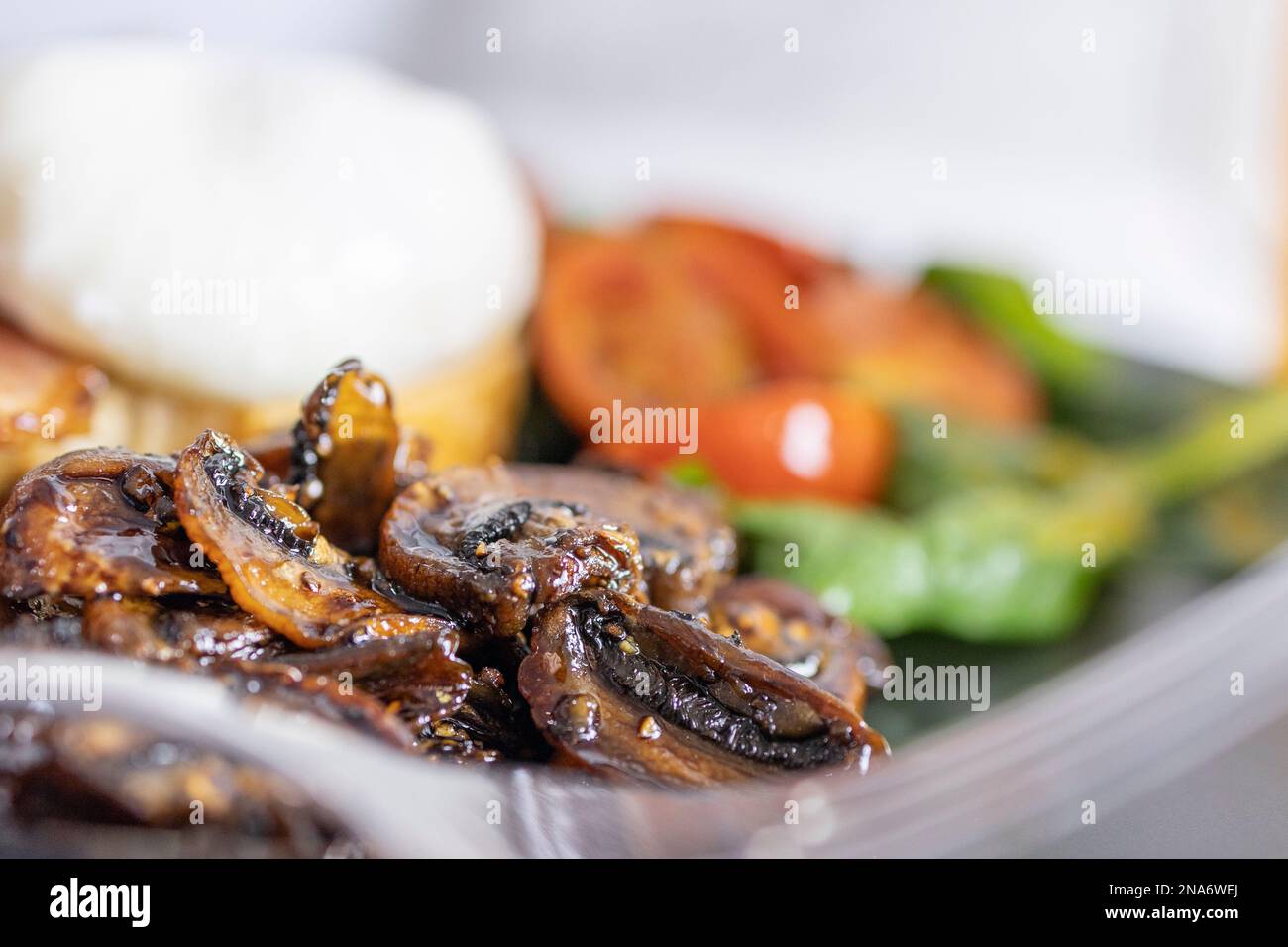Ein großes vegetarisches Frühstück mit pochierten Eiern auf Toast mit gebratenen Tomaten und Spinat; ein sehr farbenfrohes Fest für den Start in den Tag. Stockfoto