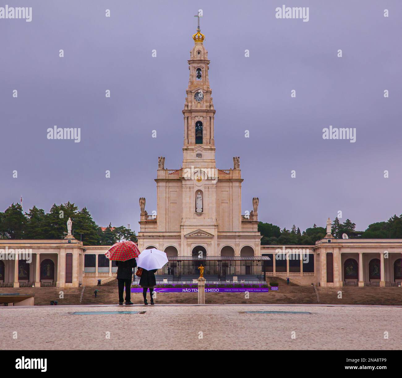 Touristen mit Sonnenschirmen, die auf die Basilika unserer Lieben Frau vom Rosenkranz, Heiligtum von Fatima, Fatima, Ourem, Portugal blicken Stockfoto