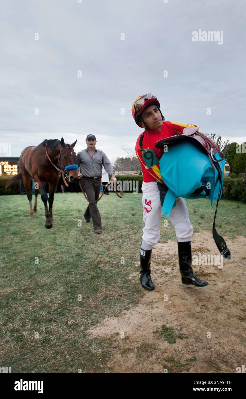 Jockey Rafael Bejarano, right, carries his saddle in the winners circle as Secret Circle is led away after winning the second division of the Southwest Stakes horse race at Oaklawn Park in Hot Springs, Ark., Monday, Feb. 20, 2012. (AP Photo/Danny Johnston) Stockfoto