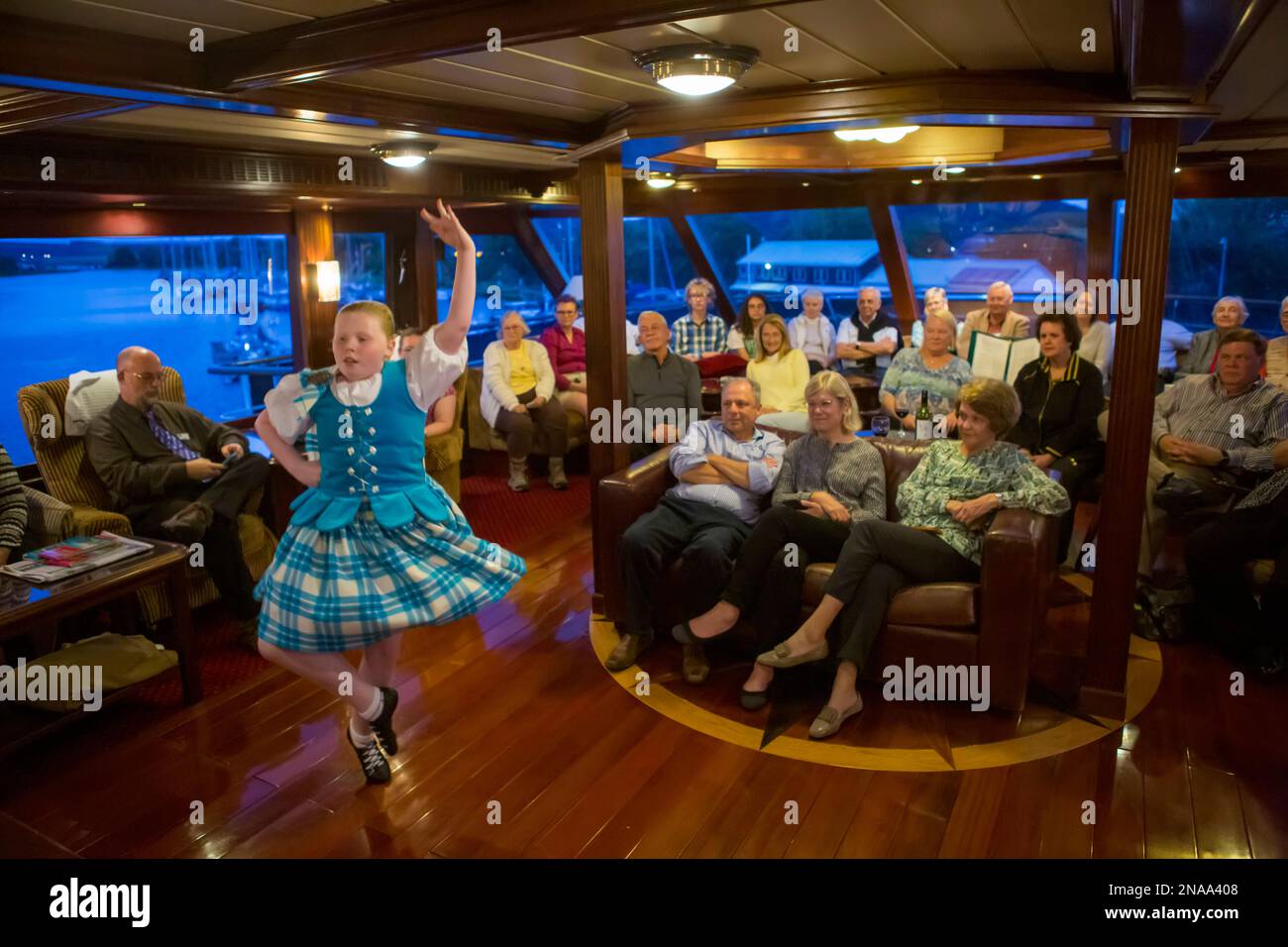 Eine junge schottische Highland-Tänzerin tritt für Reisende auf einem Boot auf dem Caledonian Canal in Inverness, Schottland. Stockfoto