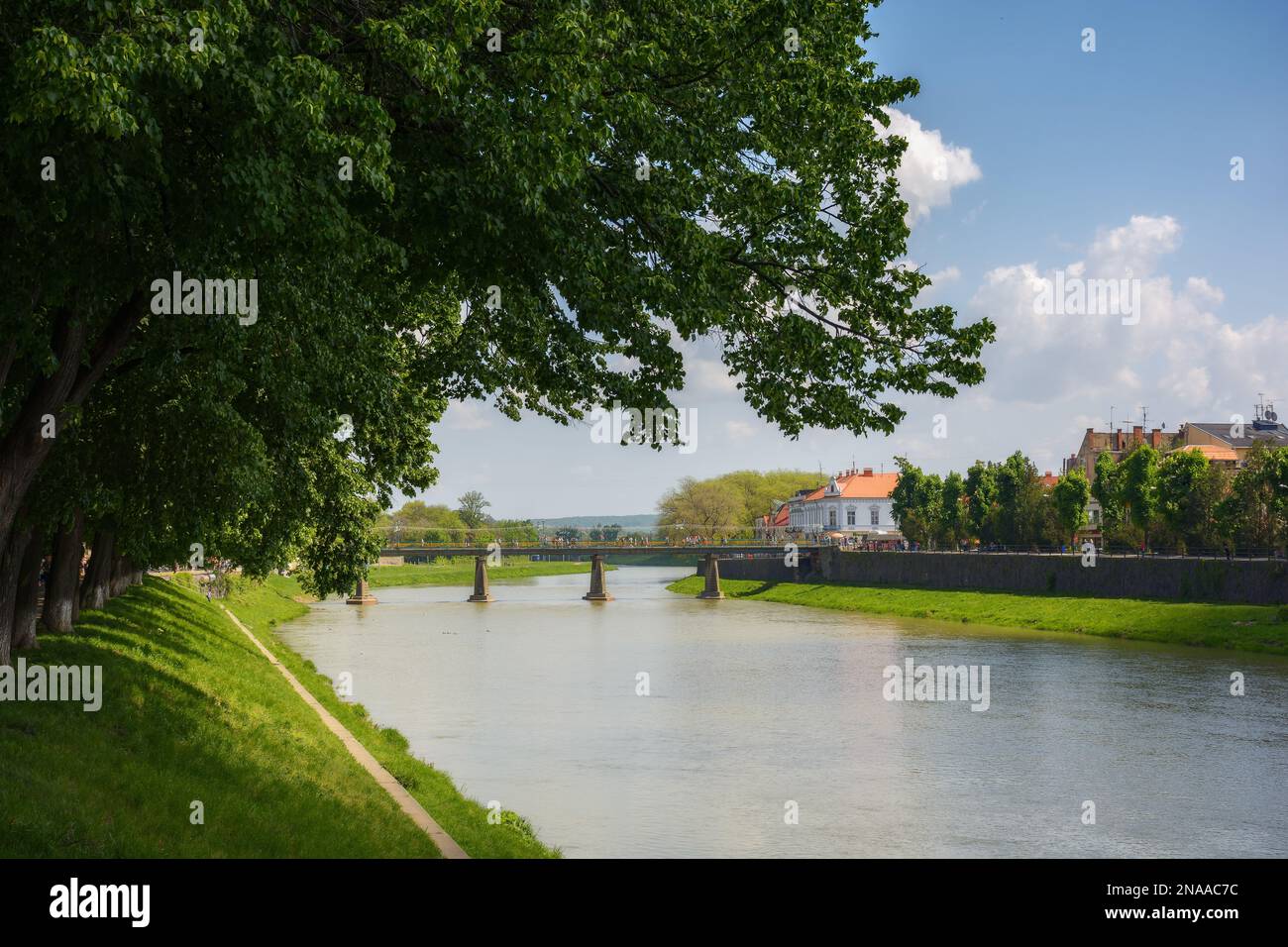 uschhorod Stadtbild mit Fluss. Böschung unter den Lindenbäumen. Brücke und alte Architektur in der Ferne Stockfoto