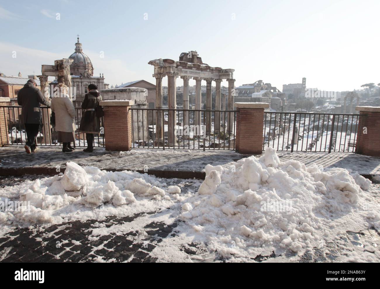 Tourists admire the view of the snow covered Roman Forum in Rome ...