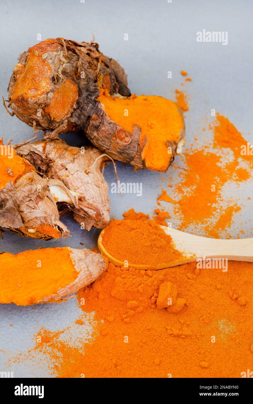 Kurkuma-Rhizome und Puder liegen flach auf Grau mit Kopierbereich Stockfoto