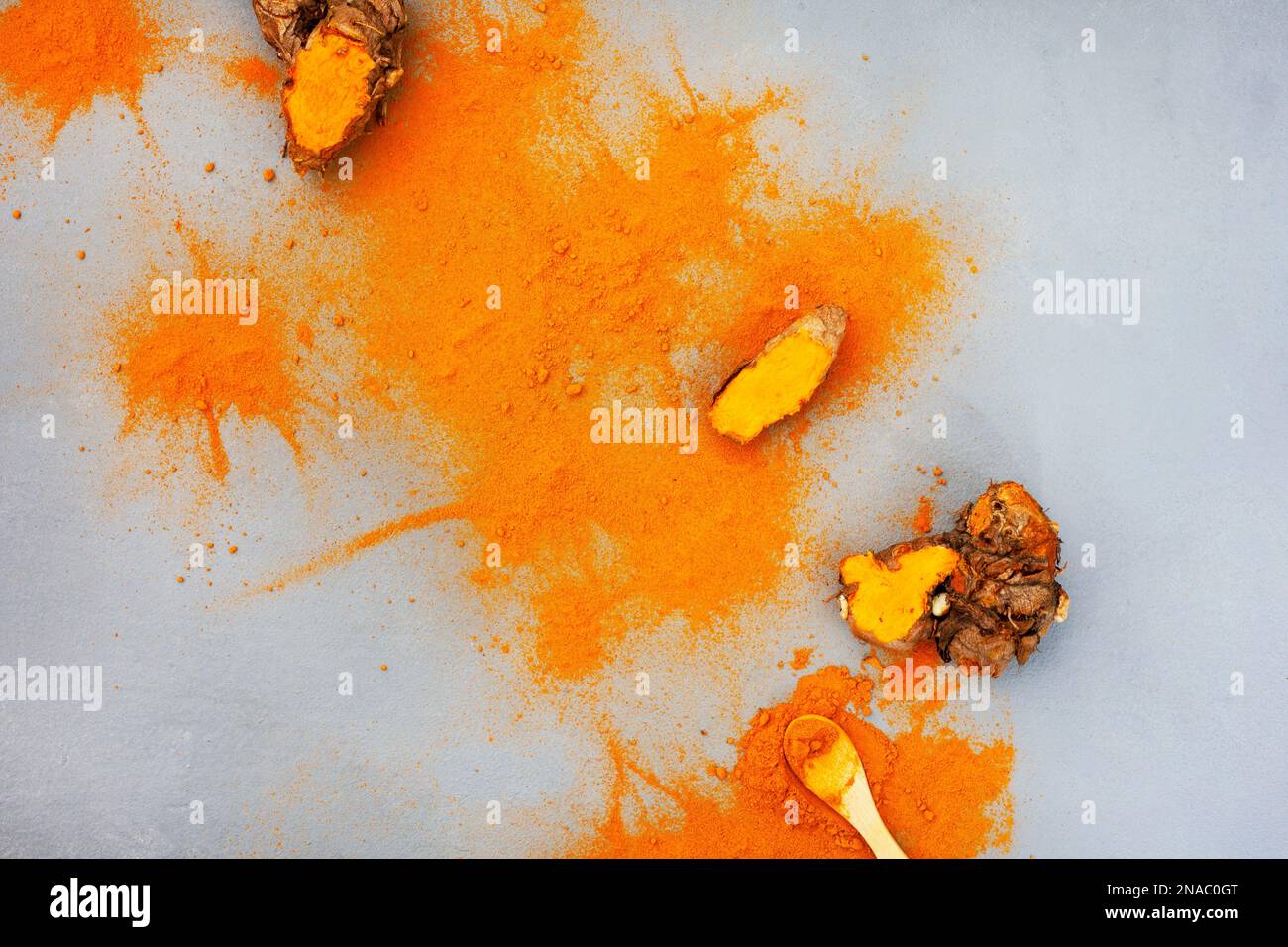 Kurkuma-Rhizome und Puder liegen flach auf Grau mit Kopierbereich Stockfoto