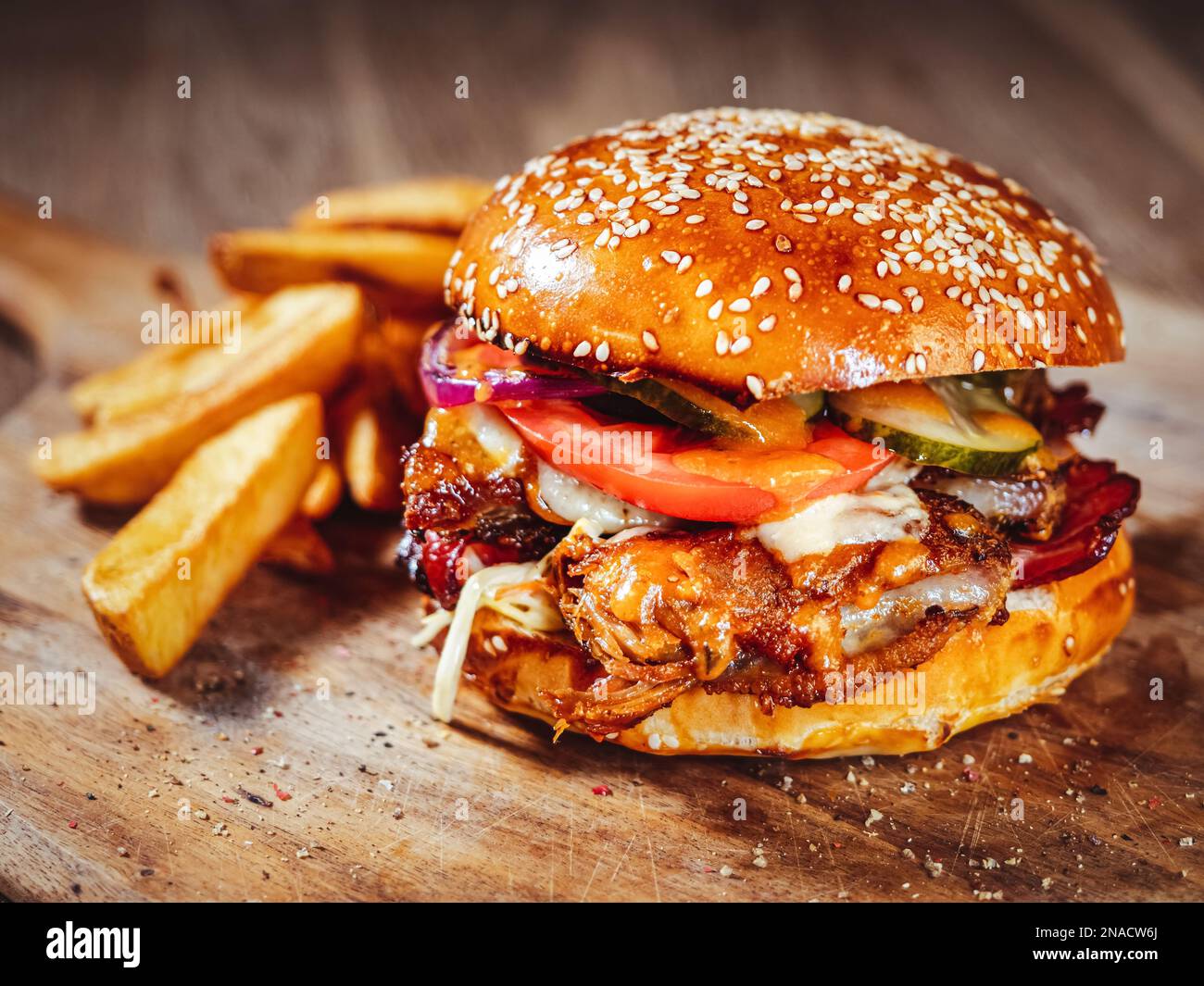 burger mit Schweinerippchen, scharfer Sauce und frischem Gemüse auf Holzbrett Stockfoto