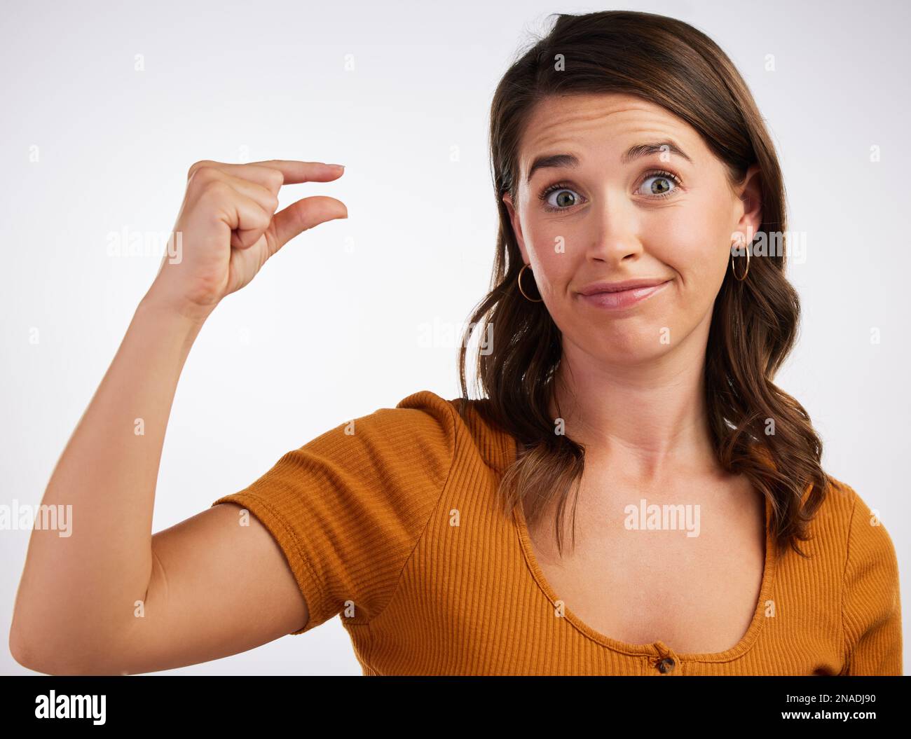 Wie viel interessiert es mich, was du verlangst? Studiofoto einer jungen Frau, die eine kleine Geste mit der Hand vor weißem Hintergrund macht. Stockfoto