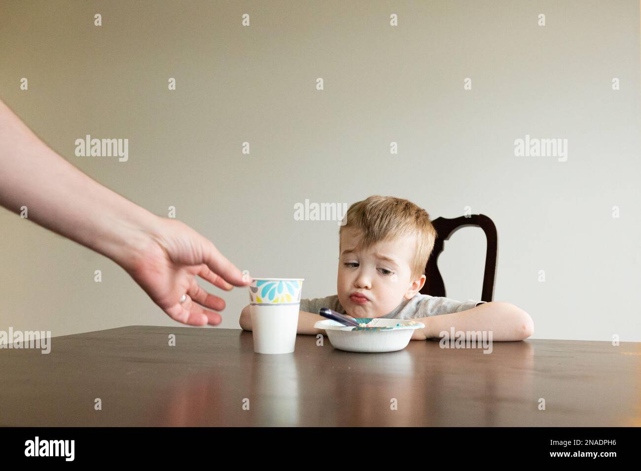 Little Boy schmollt auf das Essen, da Eltern Frühstück servieren Stockfoto