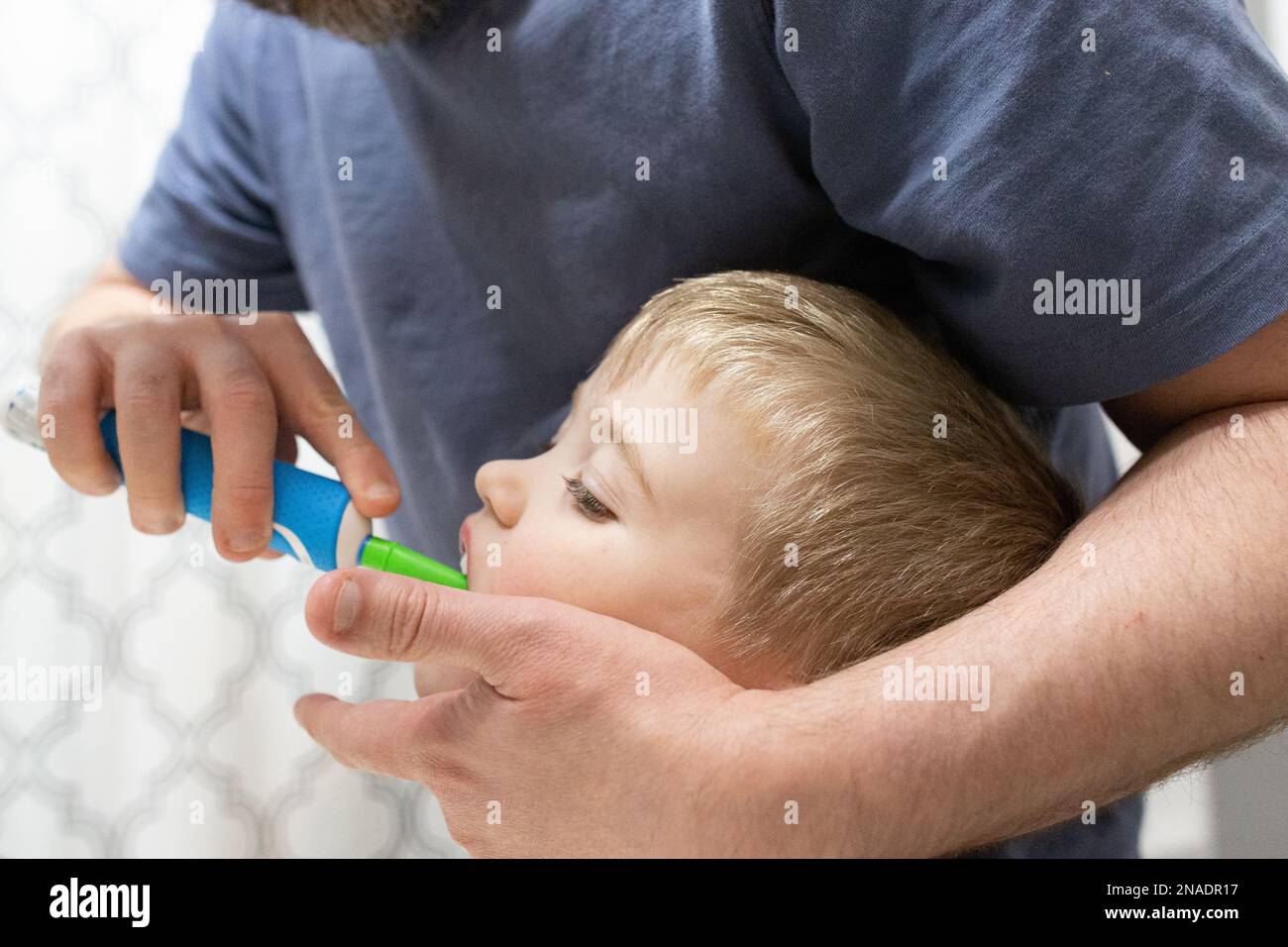 Nahaufnahme von Vater, der Sohn beim Zähneputzen mit der elektrischen Zahnbürste hilft Stockfoto