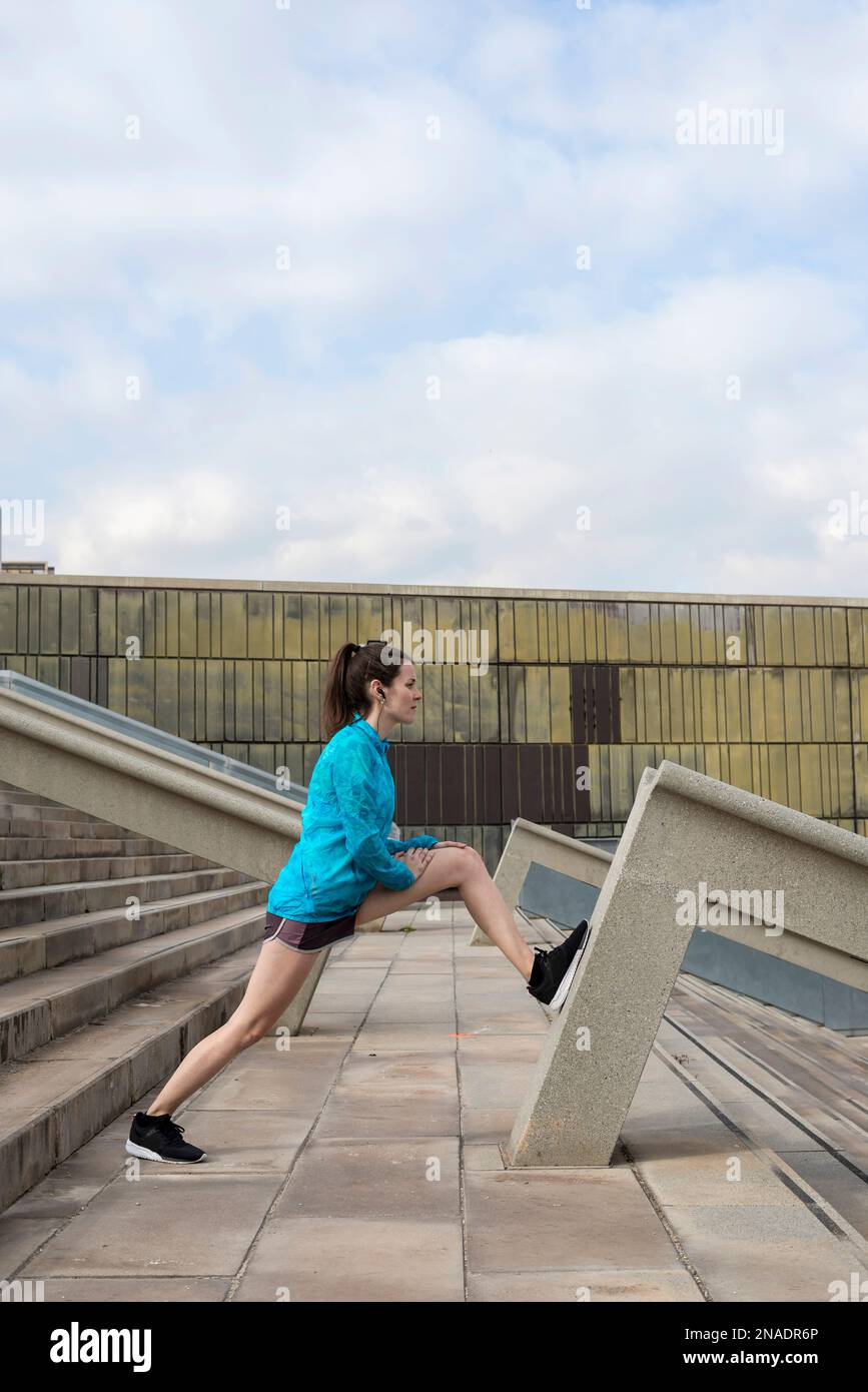 Frau in Sportbekleidung macht Stretch in städtischen Umgebung Stockfoto
