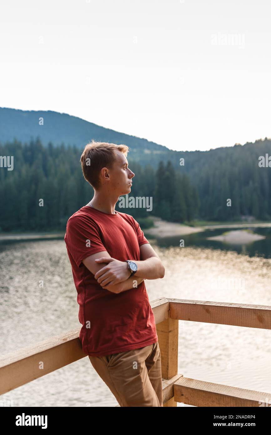 Der junge Mann ist allein in der Nähe eines Bergwaldsees Stockfoto