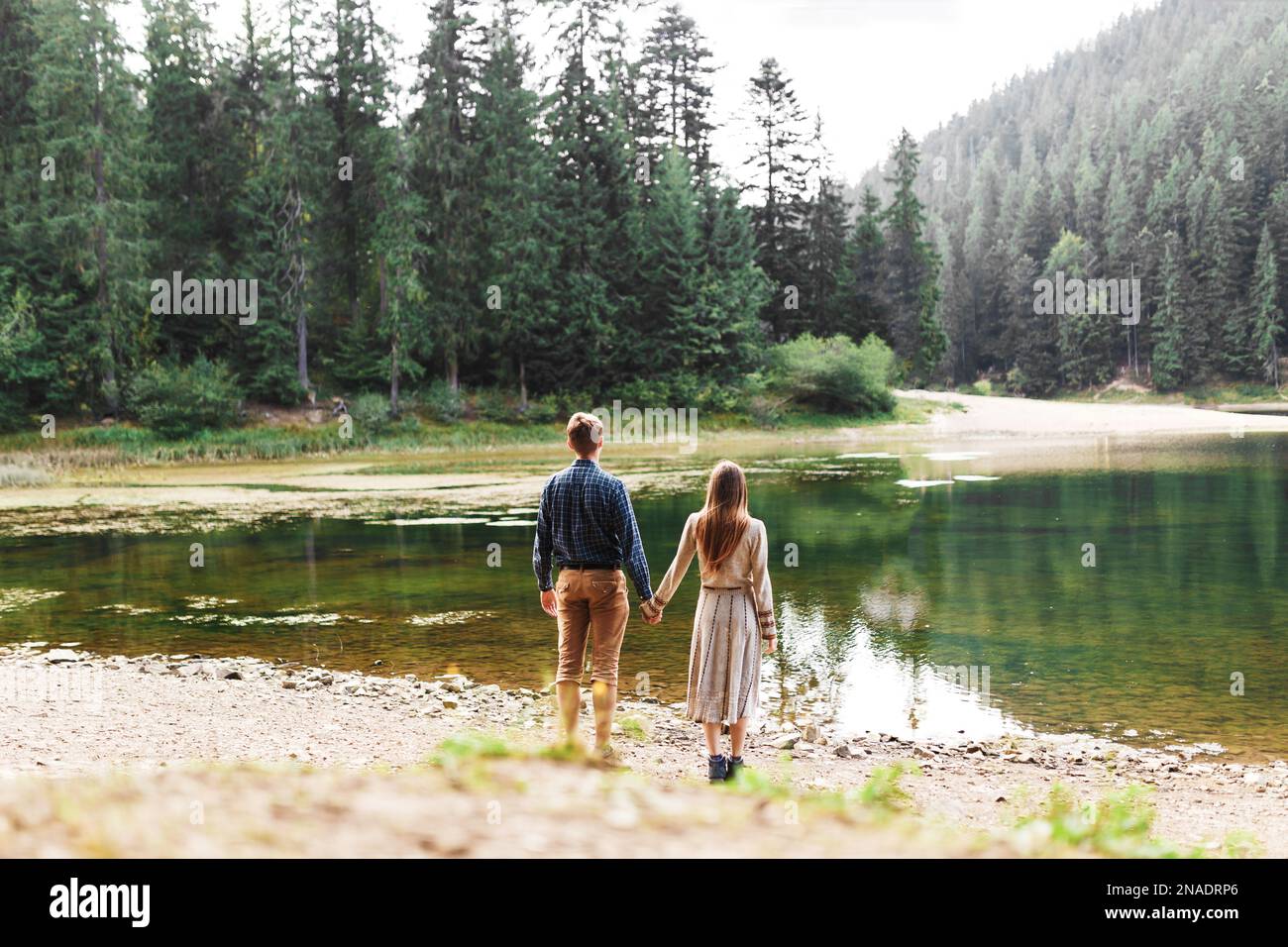Mann und Frau halten Händchen in der Nähe eines Waldsees Stockfoto