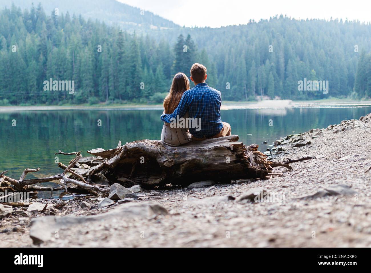 Ein Mann und eine Frau umarmen sich in der Nähe eines Waldsees Stockfoto