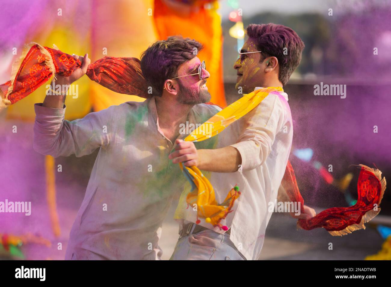 Zwei junge indische Männer mit farbigem Gesicht tanzen während des holi Color Festivals zusammen Stockfoto