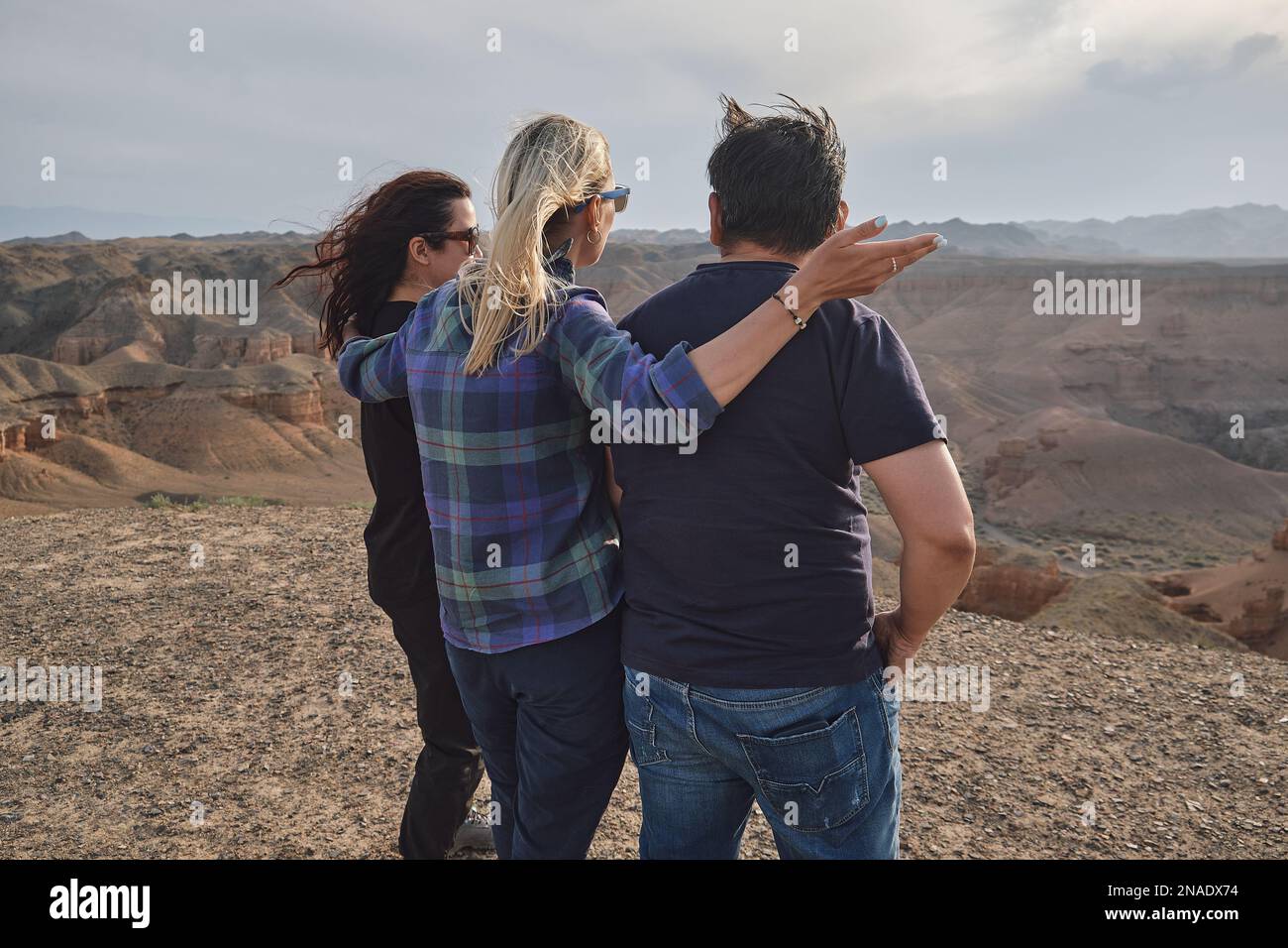 Drei Leute schauen vom Aussichtspunkt aus auf den Grand Canyon, windig Stockfoto