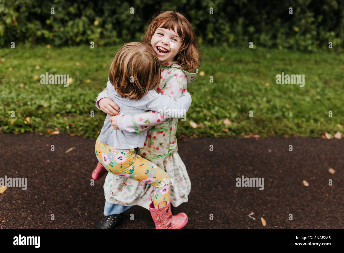An einem bewölkten Herbsttag lachen und spielen Schwestern auf dem Wanderweg Stockfoto