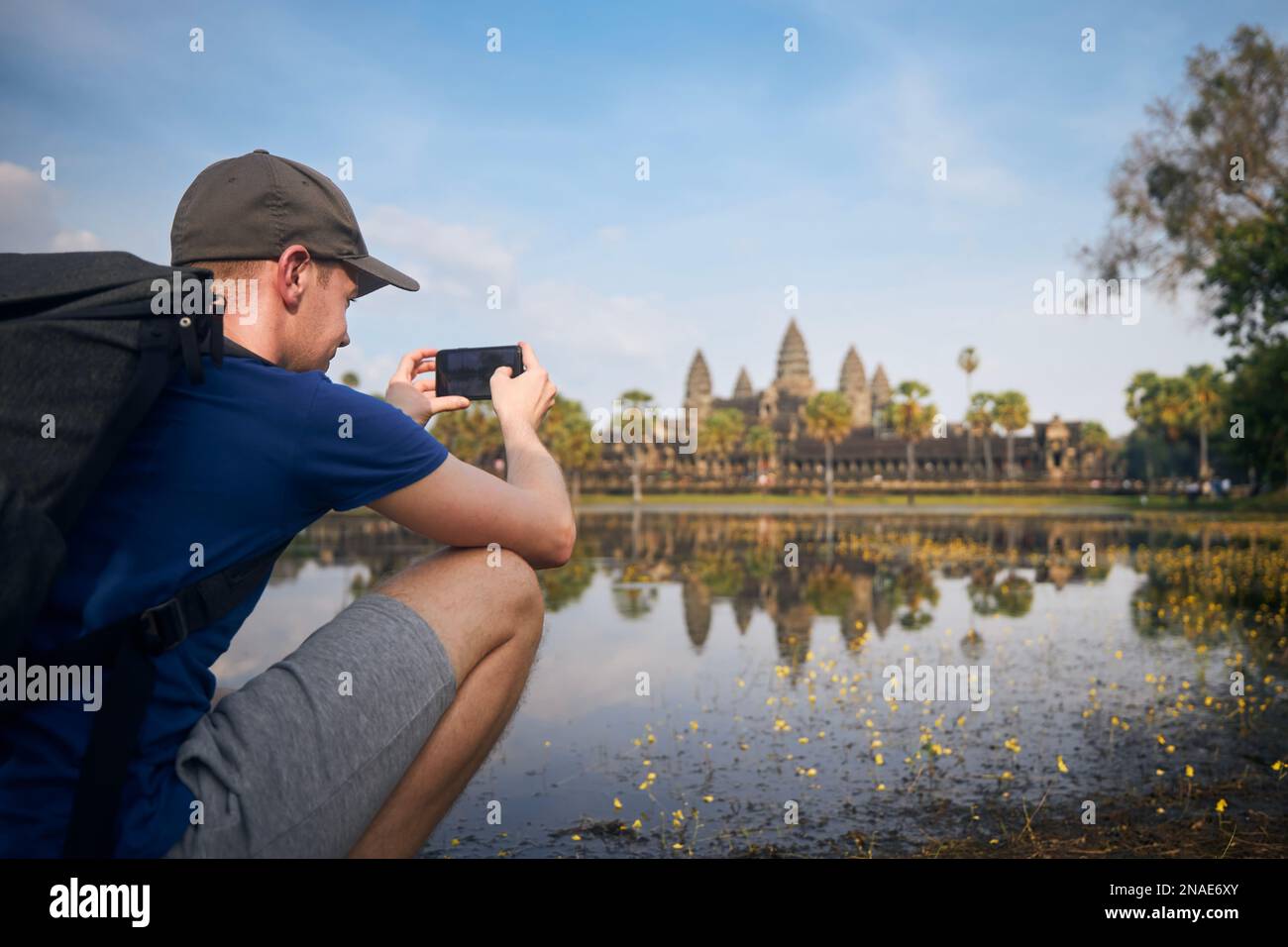 Mann mit Rucksack, der Fotos von Wasserreflexionen des Tempels im See macht. Touristen in Angkor Wat in der Nähe von Siem Reap in Kambodscha. Stockfoto