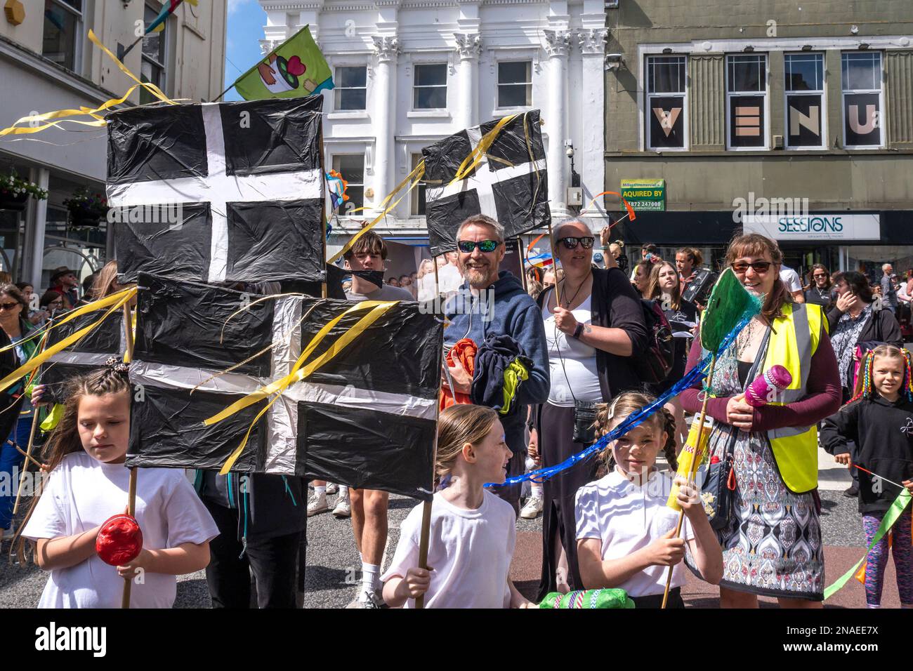 Erwachsene und Kinder, die an den farbenfrohen Mazey Day-Prozessionen in Cornwall, England, durch die Penazance fahren. Stockfoto