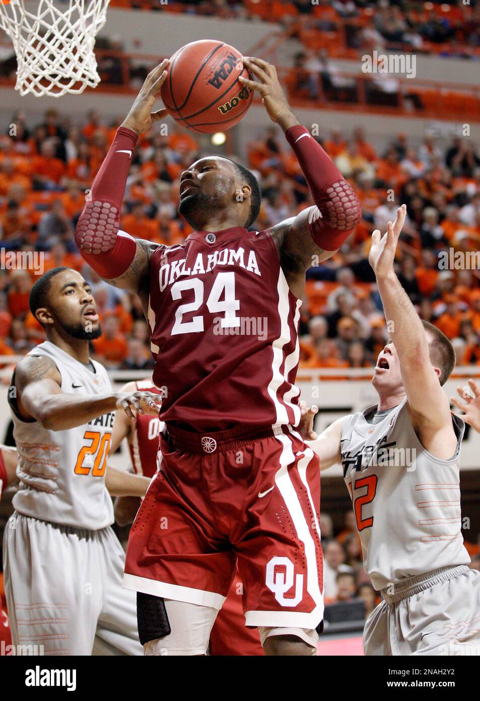 Oklahoma forward Romero Osby (24) grabs a rebound in front of Oklahoma State forward Mike Cobbins (20) and guard Keiton Page (12) in the second half of an NCAA college basketball game in Stillwater, Okla., Monday, Jan. 9, 2012. Oklahoma State won 72-65. (AP Photo/Sue Ogrocki) Stockfoto