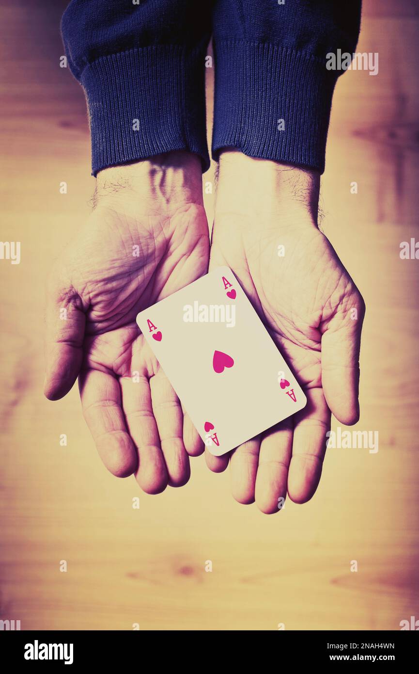 Ein Mann mit offenen Händen, der ein Herz-Ass hält und eine Karte spielt Stockfoto