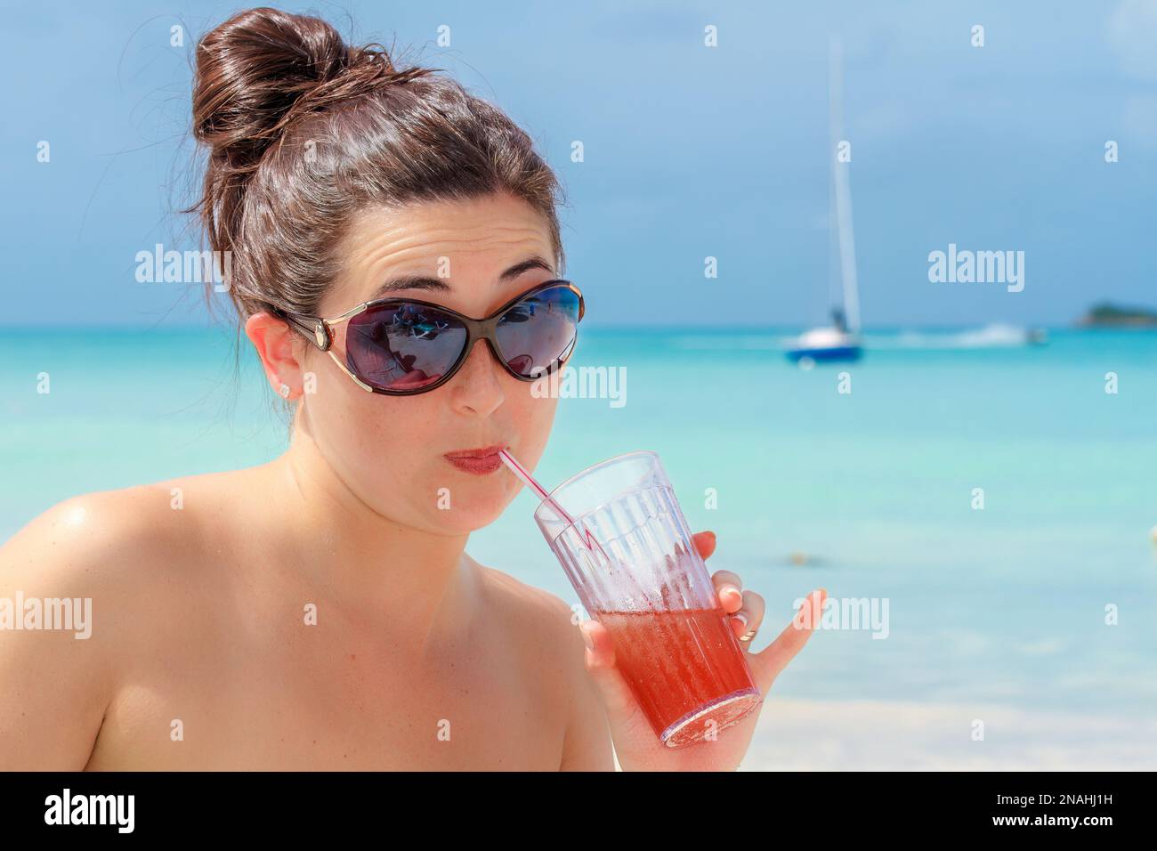 Eine junge Frau trinkt im tropischen Strandparadies Stockfoto