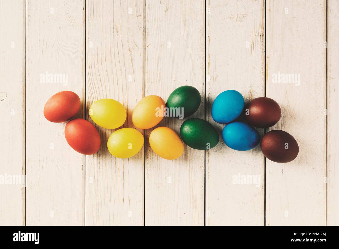 Regenbogen bunte ostereier auf Holzhintergrund. Direkt über der Tischaufnahme. Stockfoto