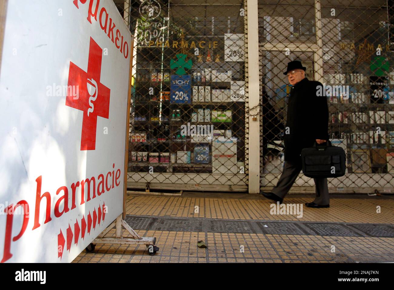 A man walks outside a shuttered Pharmacy in central Athens, on Monday, Jan. 2, 2012. Greece is already seeing its first strike of the year, with pharmacists and doctors walking off the job to protest government plans to trim their profits by cutting the retail prices of drugs. They are also demanding payment of hundreds of thousands of euros owed by social insurance funds. (AP Photo/Petros Giannakouris) Stockfoto