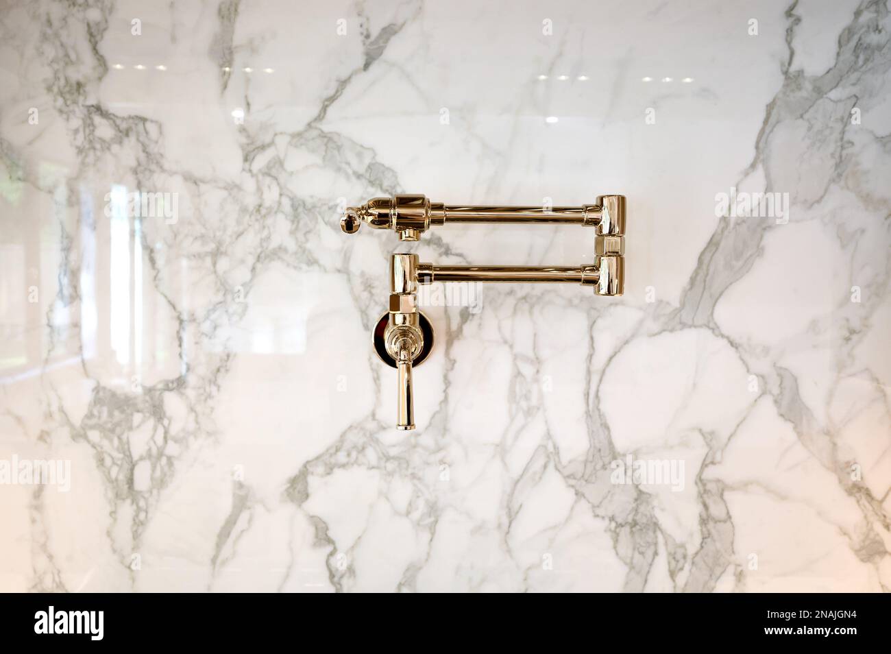 Wasserhahn auf Marmorfliesen in zeitgenössischer Küche mit goldenem Finish Stockfoto