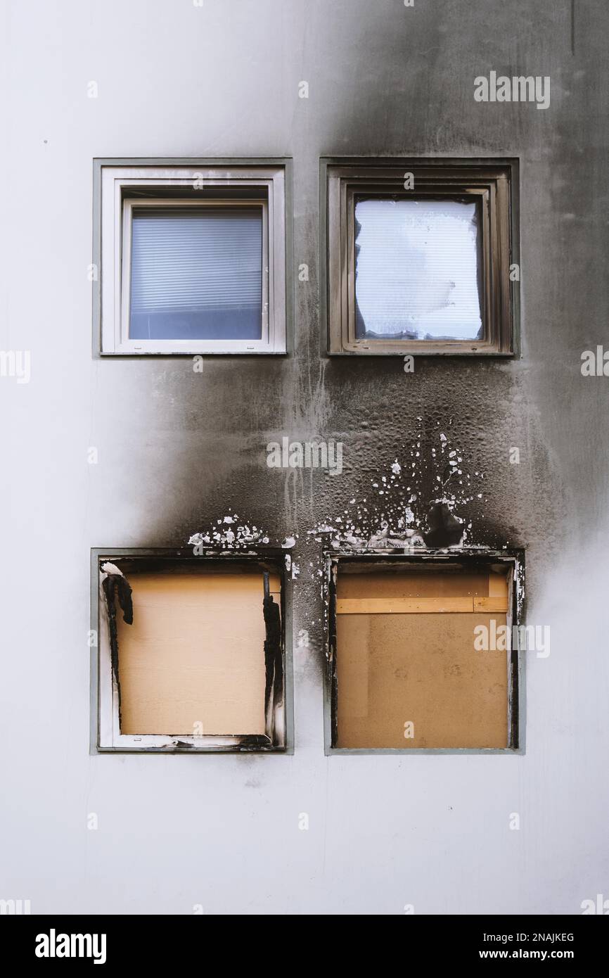 Haus oder Haus Feuer - vernagelt Fenster und verbrannt Fassade geschwärzt durch Ruß des modernen mehrstöckigen Wohnhauses Stockfoto