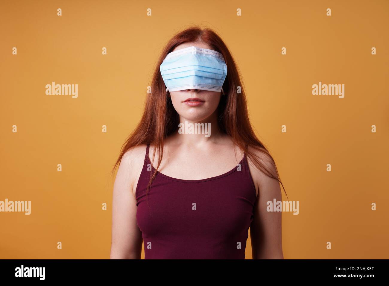 Junge Frau trägt medizinische Gesichtsmaske über ihre Augen - Lustige Corona Denier Konzept Stockfoto