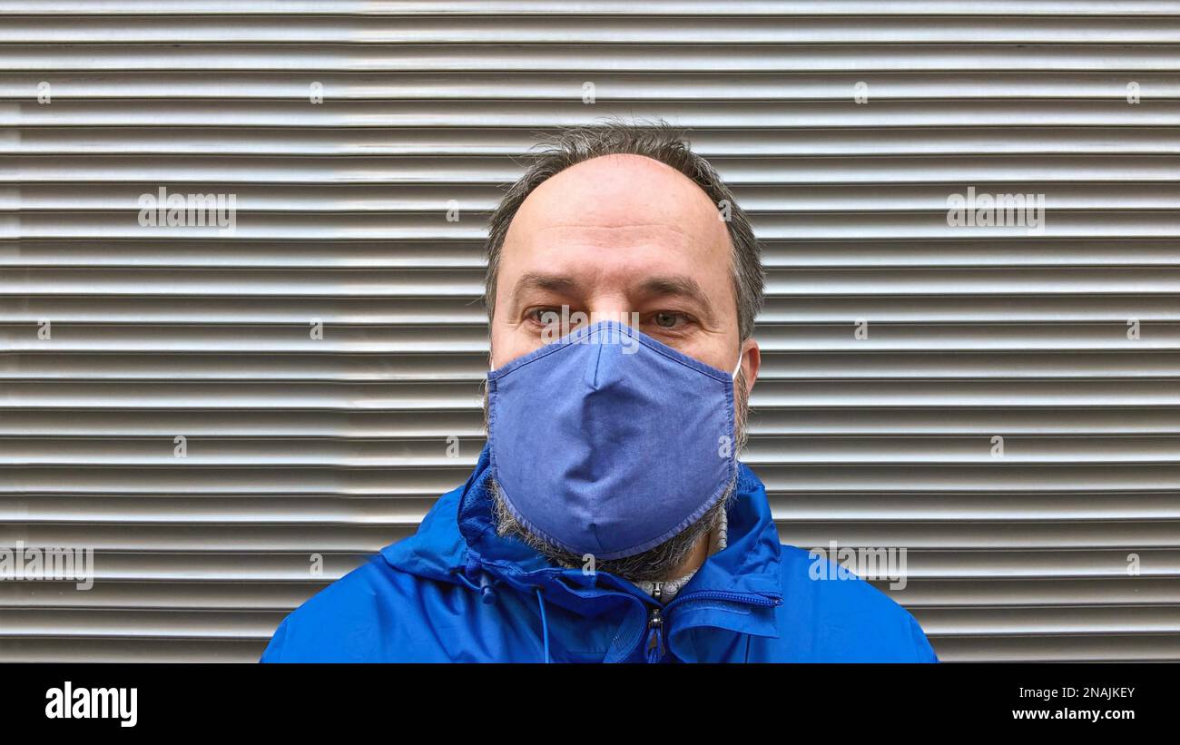 Mann mittleren Alters trägt Stoff Gesichtsmaske oder Gemeinschaftsmaske oder Alltagsmaske während Corona Covid-19 Pandemie steht außerhalb des geschlossenen Ladens Stockfoto