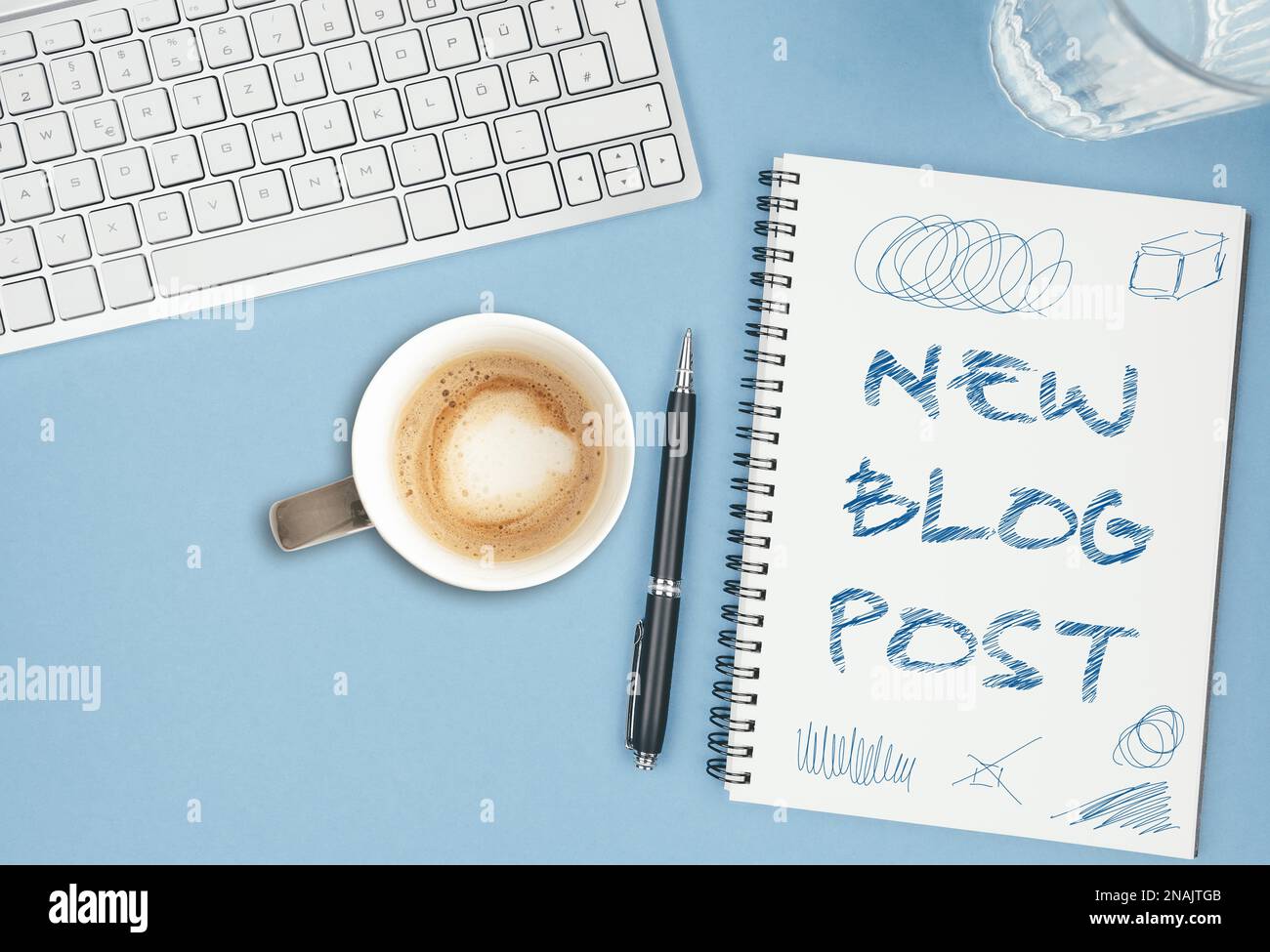 NEUER BLOG-BEITRAG auf Spiral-Notizblock auf blauem Schreibtisch mit Computertastatur gekritzelt, Blogging-Konzept Stockfoto
