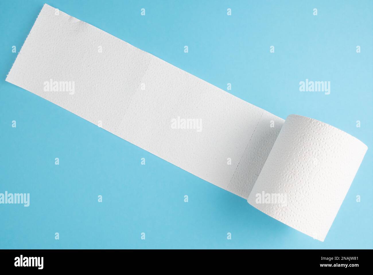 Teilweise nicht gerollte Toilettenpapierrolle isoliert auf blauem Hintergrund Stockfoto