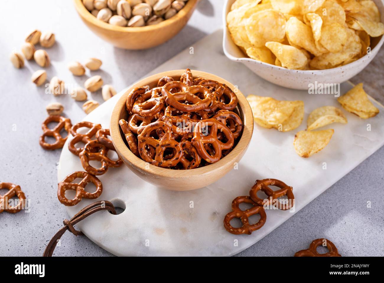 Auswahl an salzigen Snacks auf dem Tisch mit Brezeln, Pistazien und Kartoffelchips, Snacks, die gut zu Bier passen Stockfoto