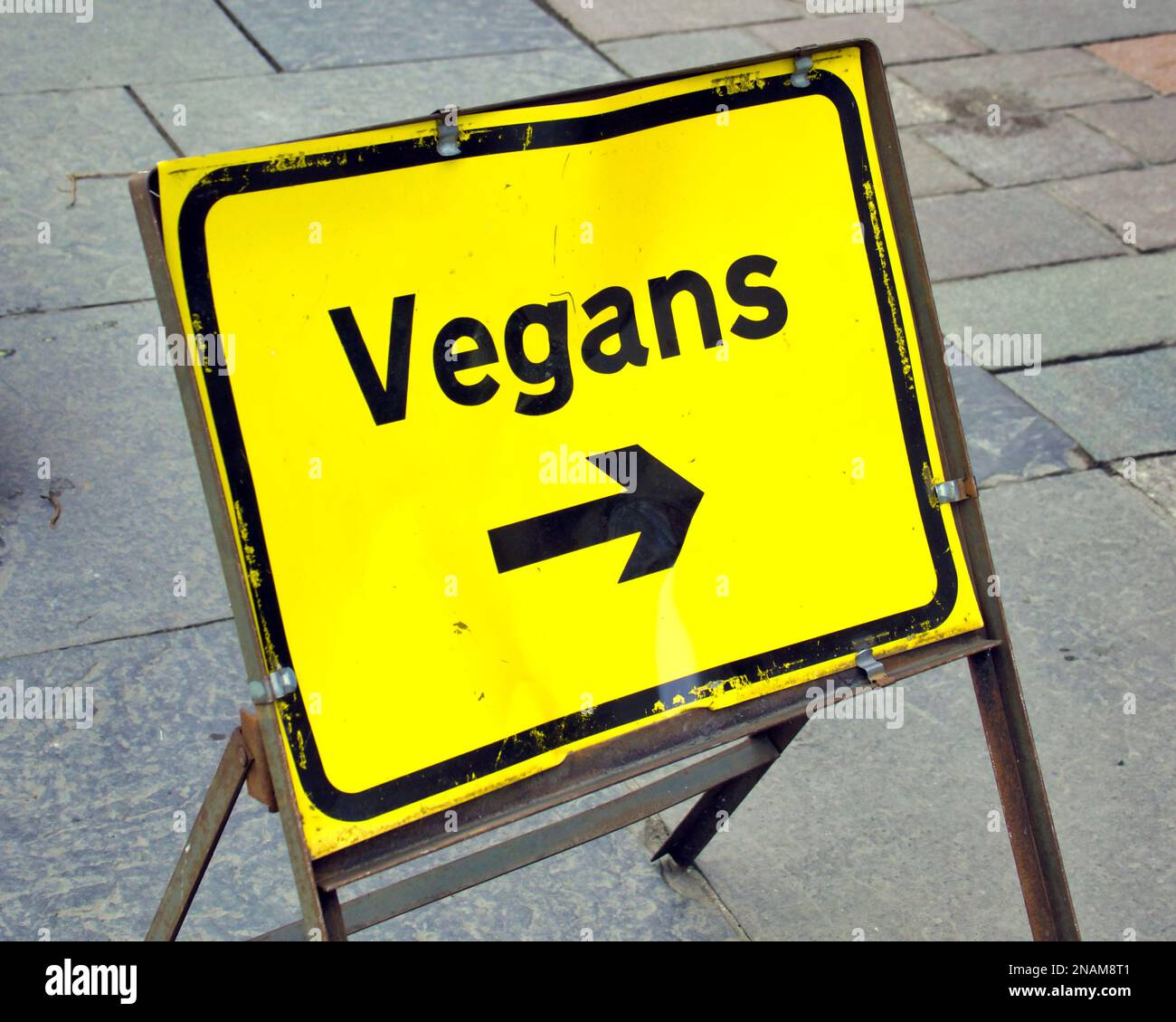 Der Pfeil des veganen Straßenschilds zeigt auf ein veganes Restaurant Stockfoto