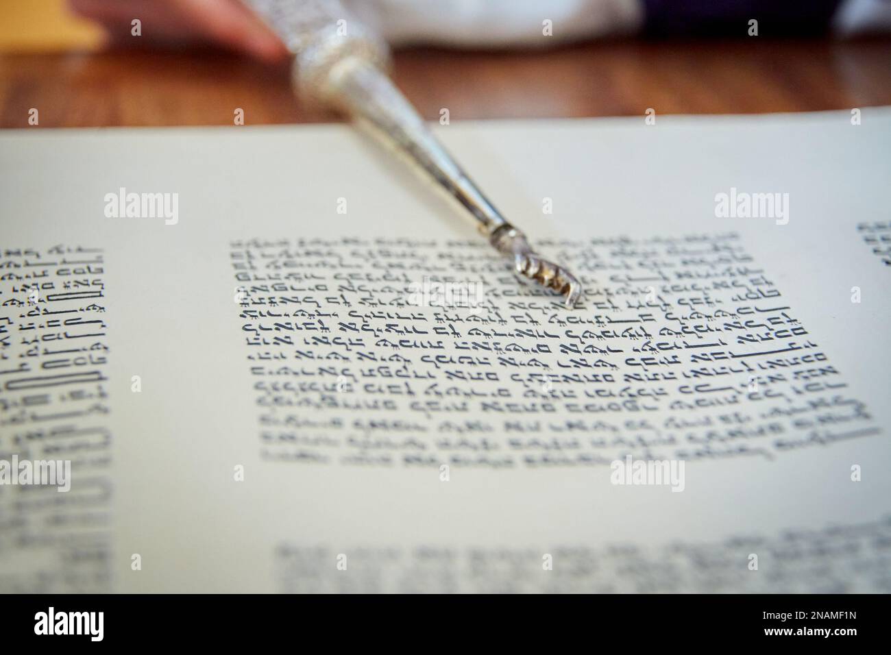 Nahaufnahme von Yad, der auf hebräische Briefe in Torah Scroll zeigt Stockfoto