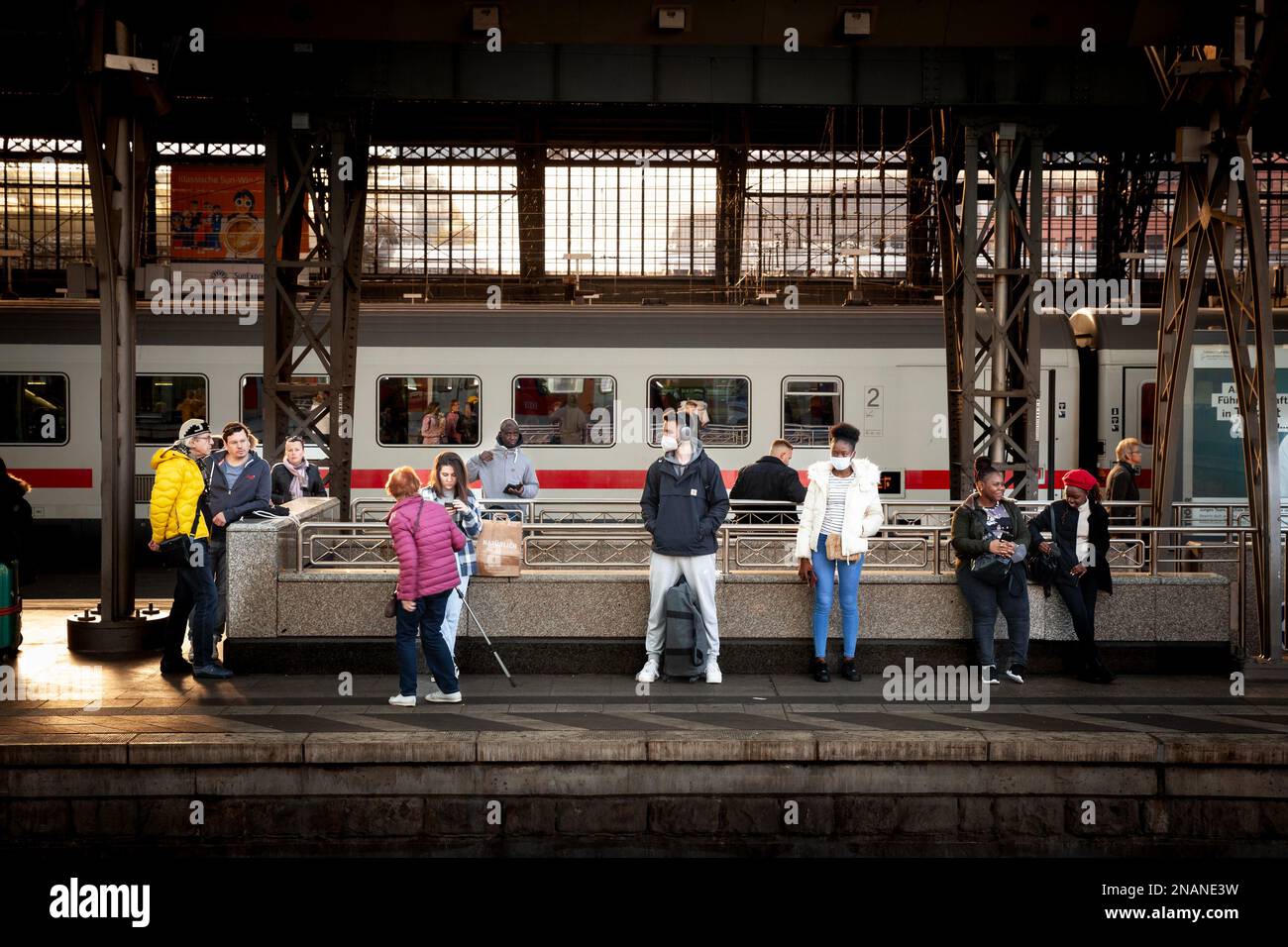 Bild von Männern, die auf den Bahnhöfen des Kölner hauptbahnhofs auf einen Zug warten und während der Coronavirus-Gesundheitskrise Covid 19 Gesichtsmasken trugen Stockfoto