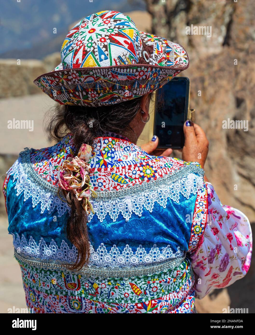 Indigene, ranghöchste peruanische Quechua-Frau in traditioneller Kleidung, die mit ihrem Smartphone, Cusco, Peru, Fotos macht. Moderne Technik in Gemeinden. Stockfoto