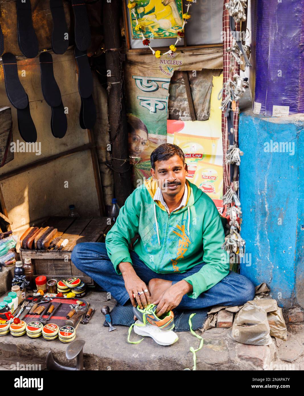 Lokaler Ausbesserer, der Schuhe und Schuhputzservice an einem kleinen Straßenstand in Fariapukur, Shyam Bazar, Kalkutta, Westbengalen, Indien repariert Stockfoto