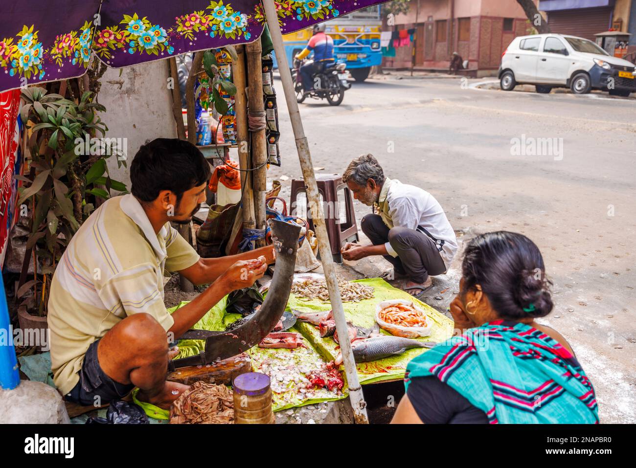 Einheimischer Straßenhalter entfernt Waagen, die Fisch für den Verkauf an einem typischen Straßenstand in Fariapukur, Shyam Bazar, Kalkutta, Westbengalen, Indien vorbereiten Stockfoto