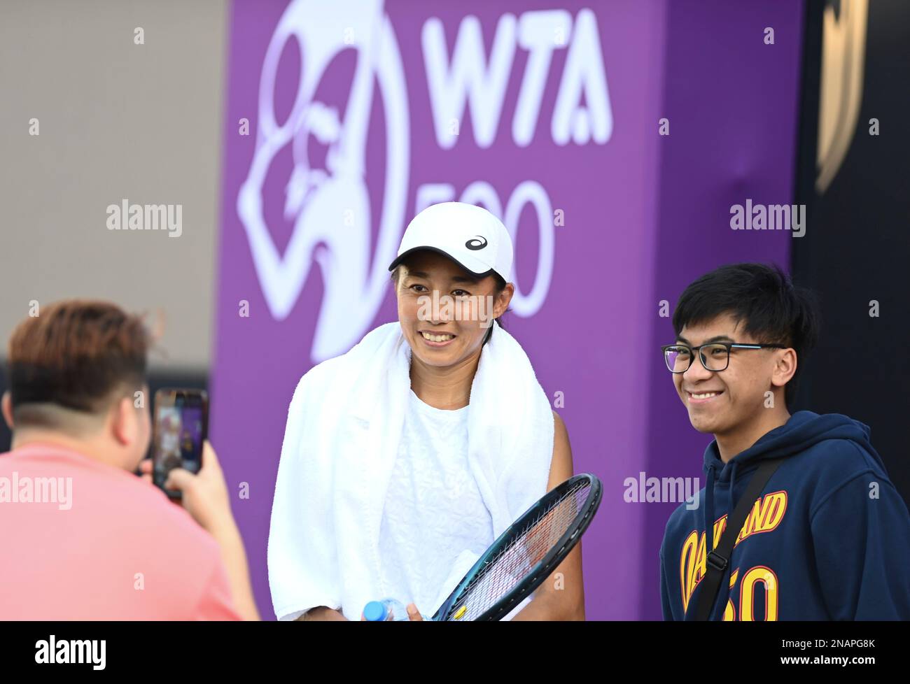 (230213) -- DOHA, 13. Februar 2023 (Xinhua) -- Zhang Shuai (C) aus China stellt Fotos mit einem Fan nach einem Training vor dem WTA500. Qatar Open 2023 in Doha, Katar, 13. Februar 2023. (Foto: Nikku/Xinhua) Stockfoto