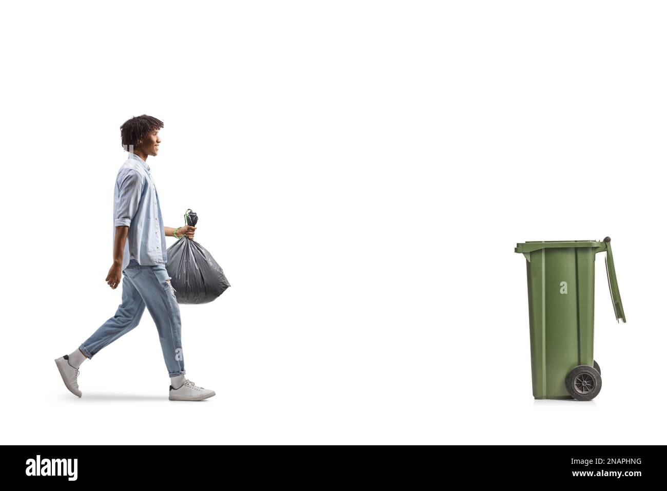 Profilaufnahme eines afroamerikanischen Mannes, der auf einen Müll zugeht und einen Plastikbeutel mit sich führt, isoliert auf weißem Hintergrund Stockfoto