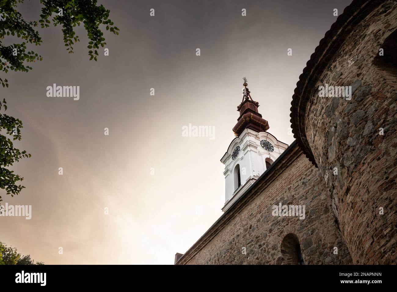 Bild des ikonischen Uhrturms der serbischen orthodoxen Kirche von Stari Slankamen, in Serbien, aufgenommen während eines warmen Sonnenuntergangs. Stari Slankamen auch bekannt Stockfoto