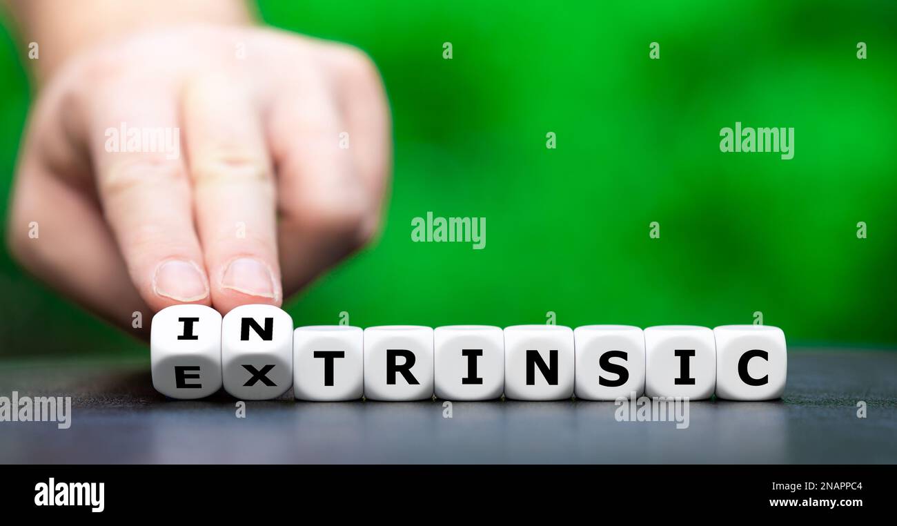 Die Hand würfelt und ändert das Wort extrinsisch in intrinsisch. Stockfoto